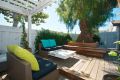 Backyard deck, view of pepper tree with bench seating around it